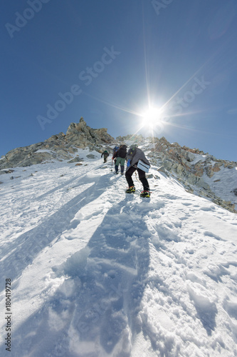 Tied climbers climbing mountain with snow field tied with crampons with ice axes and helmets © Baikal360