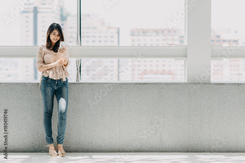 Beautiful Asian woman using smartphone in modern office building