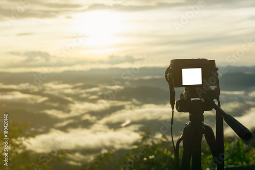 The Mirrorless camera put on the tripod for recording the viedo or capturing the beautiful mountain scenery with sun light in th morning.