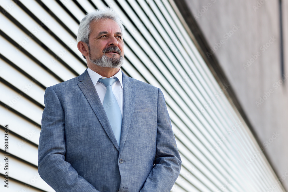 Senior businessman with arms crossed outside of modern office building. Senior businessman with arms crossed outside of modern office building.
