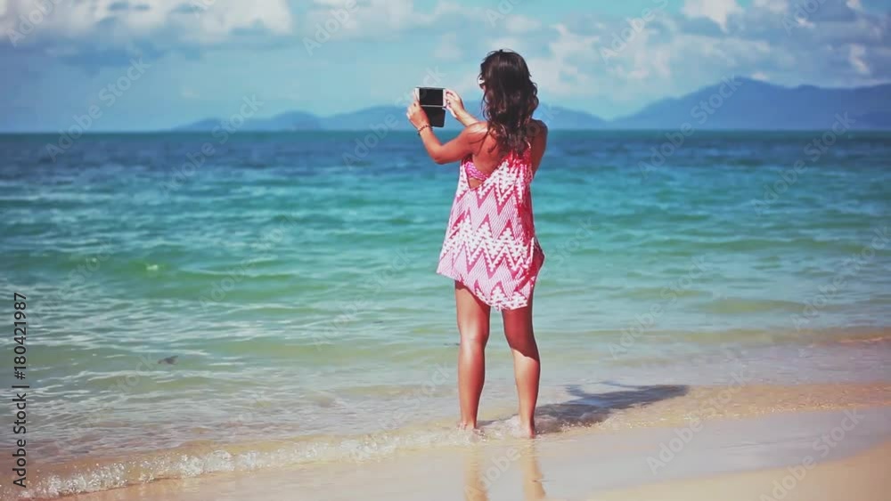 Beautiful brunette girl in a red dress and sunglasses taking selfie and picture on the sandy beach. 1920x1080 Beautiful brunette girl in a red dress and sunglasses taking selfie and picture on the sandy beach. 1920x1080