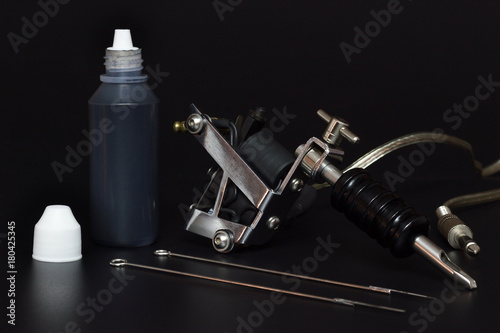 Tattoo machines and Bottles tattoo Ink in darkness. Equipment for creating artwork on human skin.