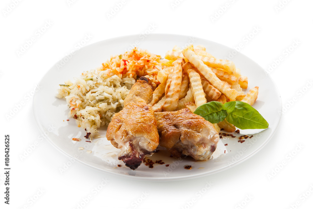 Grilled drumsticks with french fries and vegetables on white background Grilled drumsticks with french fries and vegetables on white background