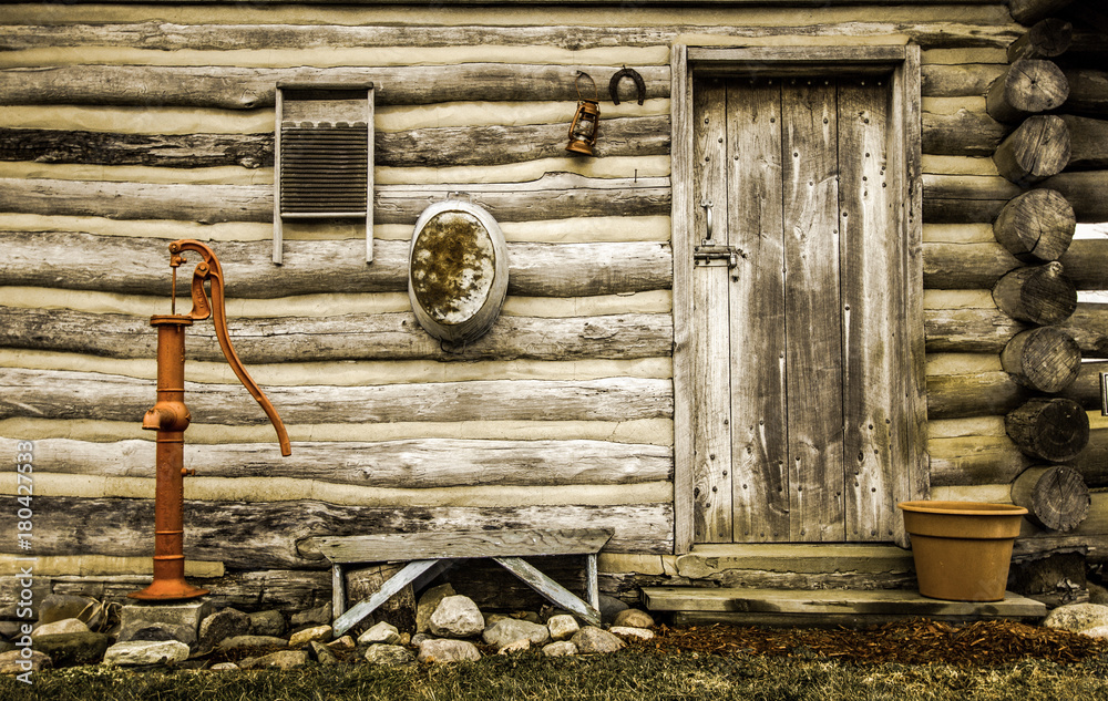 Rustic Log Cabin Exterior. Front door and exterior wall of a historical  rustic log cabin with antique décor. Stock Photo