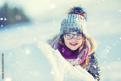 Young girl are playing with snow.Beauty Winter happy Girl Blowing Snow in frosty winter park or outdoors. Girl and winter cold weather