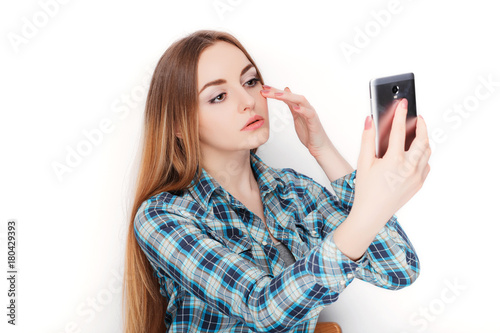 Portrait of a young adorable blonde woman in blue plaid shirt enjoying doing selfie on smartphone. photo