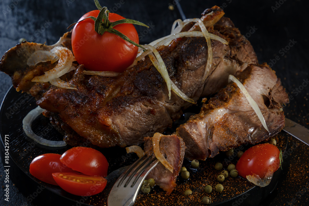 Fried lamb with vegetables. Fried meat on a black background. BBQ. Closeup. Piece of meat on the fork Fried lamb with vegetables. Fried meat on a black background. BBQ. Closeup. Piece of meat on the fork