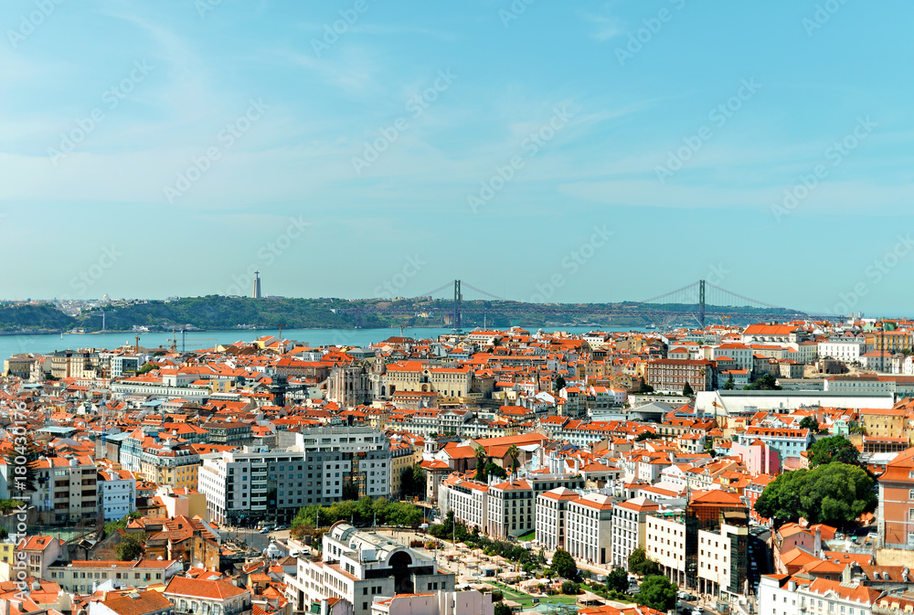 Alfama downtown and the 25 April Bridge in Lisbon, Portugal.