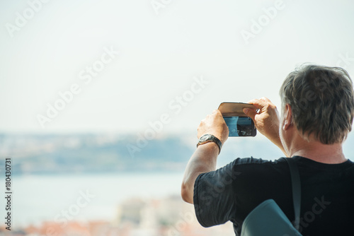 Senior man taking photos of old town.