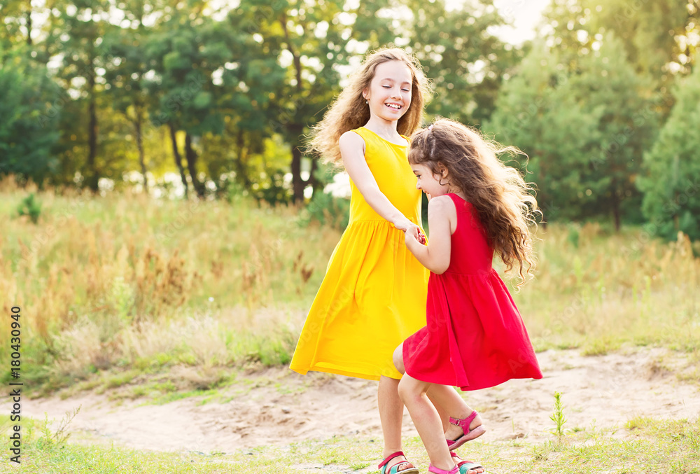 Two Happy little girl embracing and dancing at sunny summer day Two Happy little girl embracing and dancing at sunny summer day