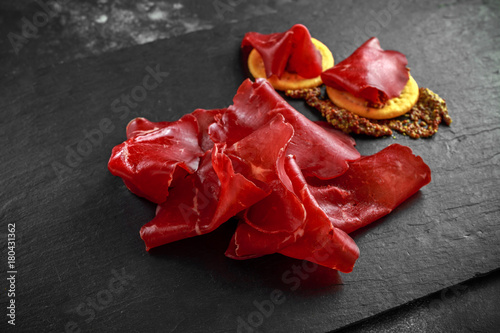 italian air-dried salted bresaola beef thinly sliced and served on stone board. Perfect appetizer photo