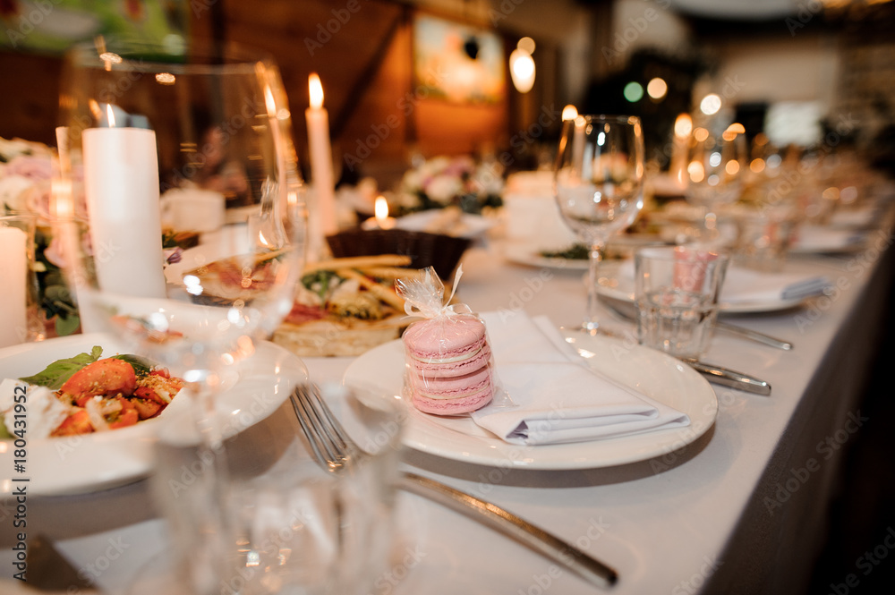 Festive table covered with white tablecloth, decorated with candles and served with tasty and elegant dishes