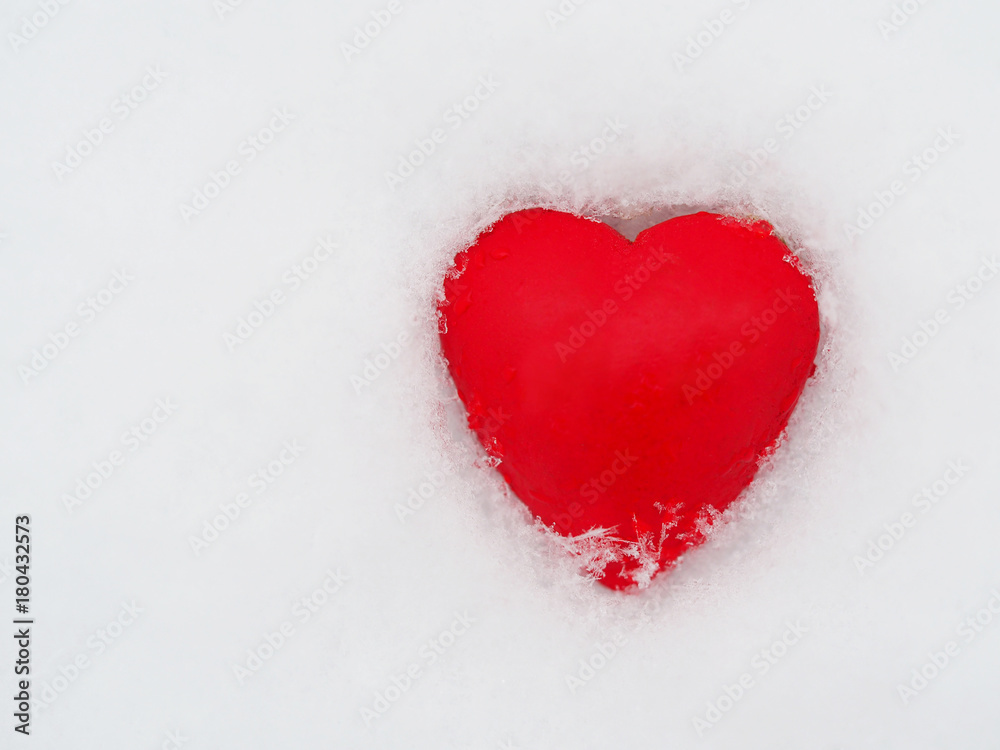 Red heart lies on the snow, the symbol of Valentine's Day, heart melts snow