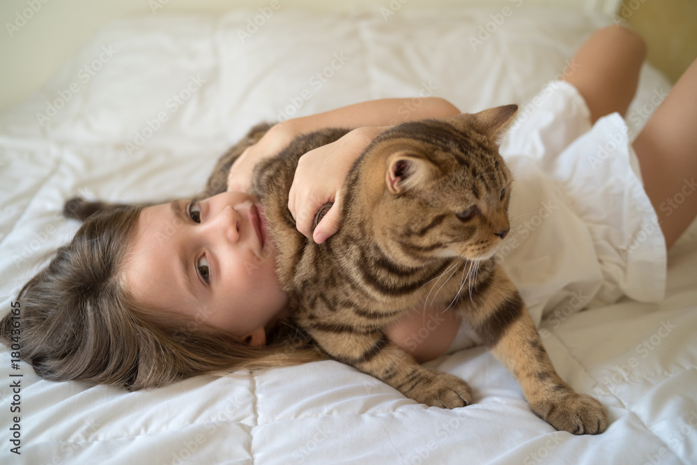Caucasian girl hugging cat on bed Caucasian girl hugging cat on bed