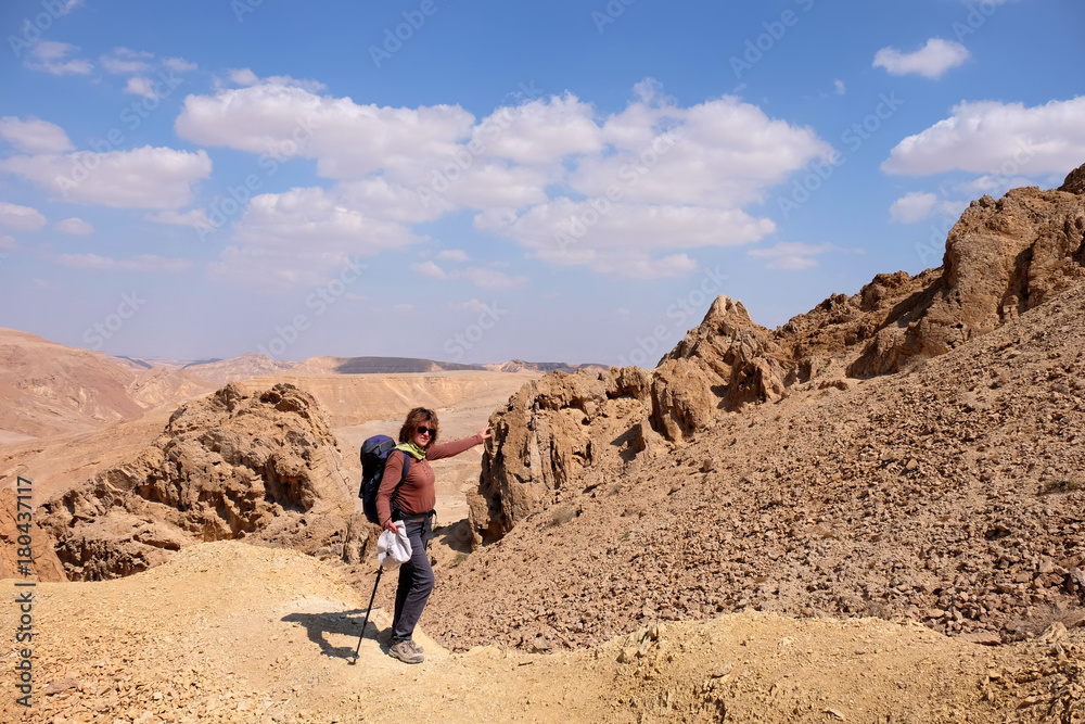 Female hiker touching remote rock for fun in Negev desert mountains.