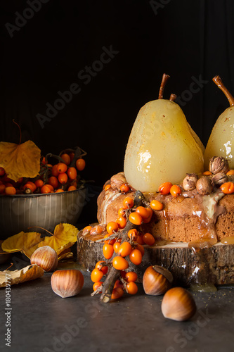 Autumn meal. Pie with pears, sea buckthorn and nuts. Dark background.