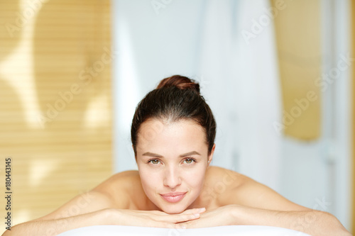 Young woman with natural beauty enjoying spa procedure in salon
