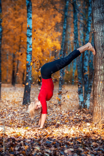 beautiful woman doing yoga outdoors On yellow leaves photo