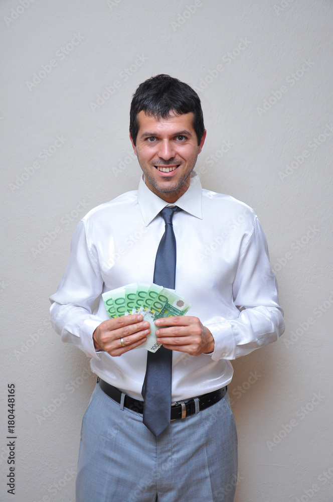 Happy and successful businessman holding pile of money. Young man with pile of euro banknotes Happy and successful businessman holding pile of money. Young man with pile of euro banknotes