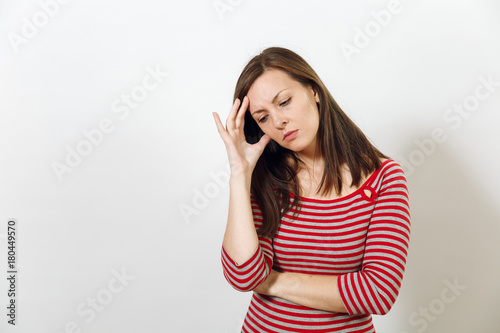 Pretty European worried and pensive brown-haired woman with healthy clean skin and headache, dressed in red and grey clothes lost in thought and conjectures, on a white background. Emotions concept.