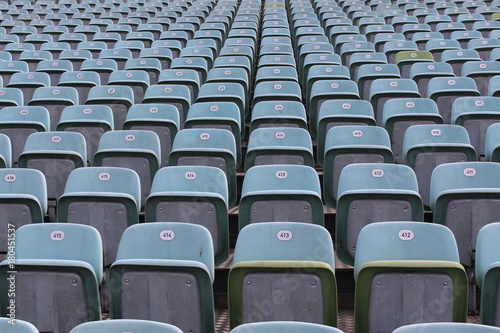 Rows of numbered empty plastic seats at an open-air amphitheater.