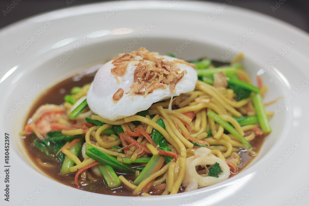 stir fried egg yellow noodle top with poached egg
