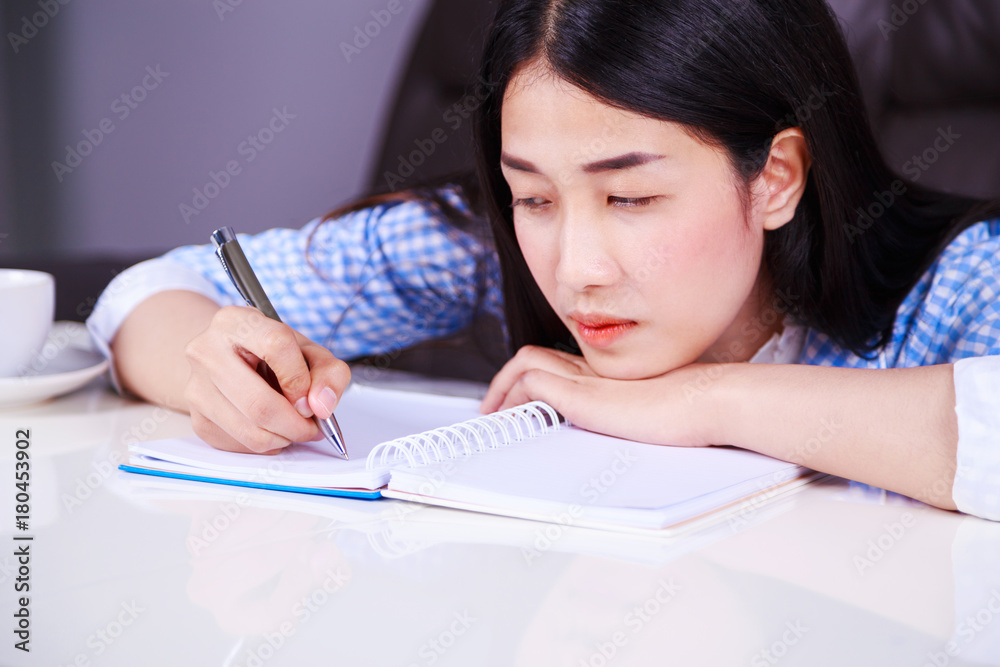 stressed business woman sitting at her desk and writes a note on the notebook stressed business woman sitting at her desk and writes a note on the notebook
