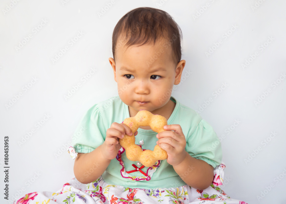Little girl used two hands holding donut and eat. Sweet dessert. Portrait on white background. Asian children. Little girl used two hands holding donut and eat. Sweet dessert. Portrait on white background. Asian children.