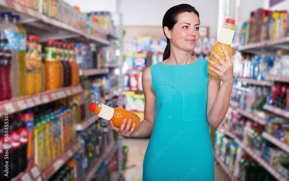 Woman in the supermarket choosing  juice in bottle