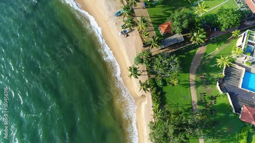 Aerial of sea waves and sandy beach near the hotel that washing by sea waves in Sri Lanka