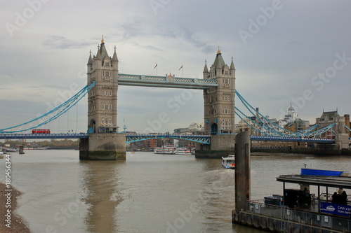 Most Tower Bridge w Londynie, Wielka Brytania, widok z brzegu Tamizy, pochmurny dzień #180456344