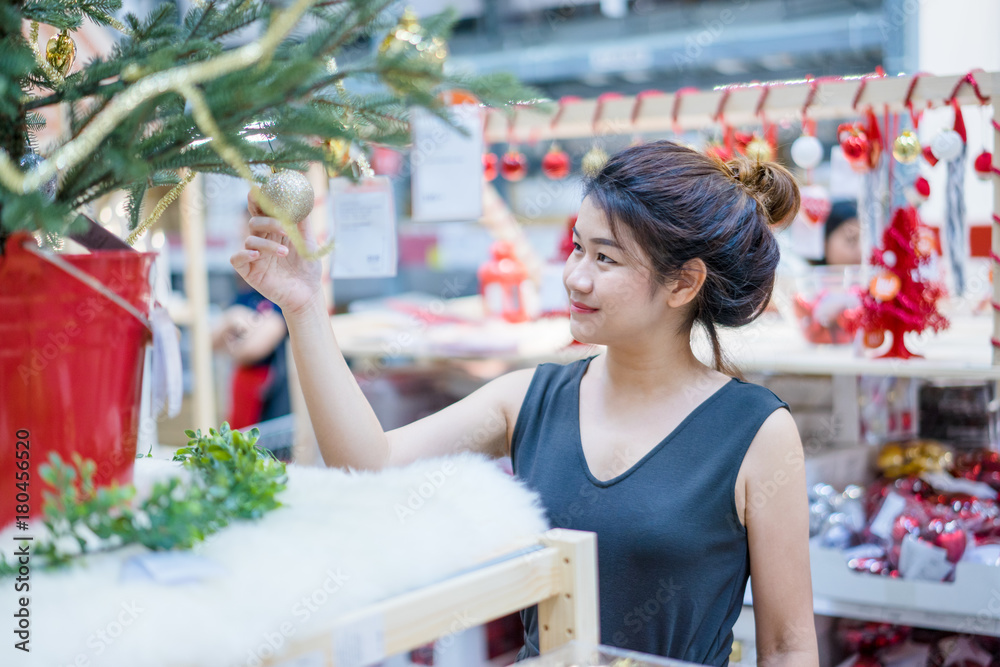 Portrait of smiling young asian woman choosing gifts and decorations at Christmas fair and new year at department store.