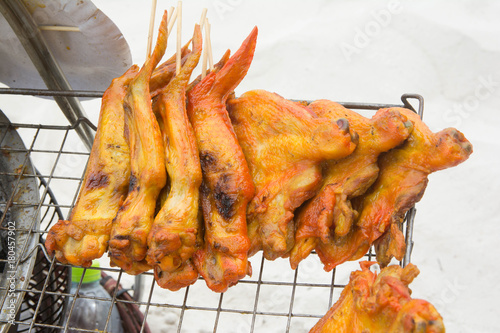 Barbecue chicken on steel grating selling on white sand beach.