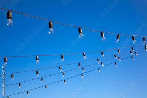 Vintage antique hanging light bulbs at the blue sky. Holidays and business good idea concept.