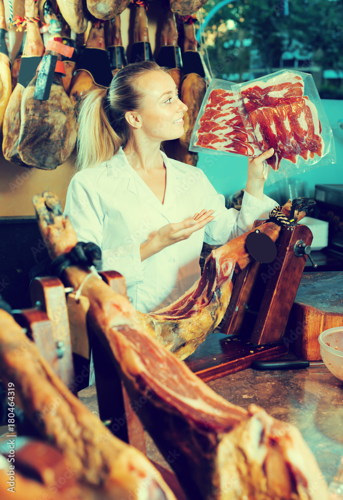 Woman in uniform selling prosciutto meat