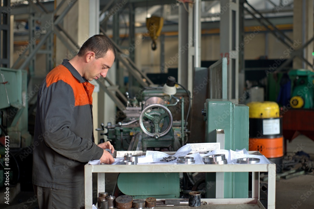 metalworking industry: factory man worker in uniform working on lathe machine in workshop metalworking industry: factory man worker in uniform working on lathe machine in workshop