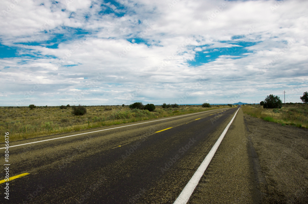Straight wet road leading throught Arizonas beautiful prairie