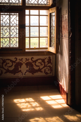 Sunlight streams through an old wooden window in an old english house with ornate decor