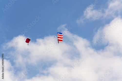 Two parachutists skydiving with colorful parachute clouds blue sky background