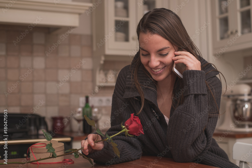 Beautiful young woman is sitting in the kitchen after Valentine's day in the morning