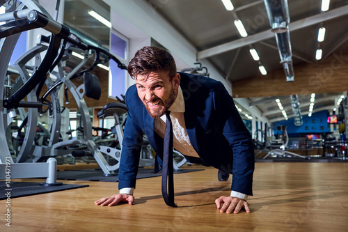Businessman doing push-ups from the floor in the gym. photo