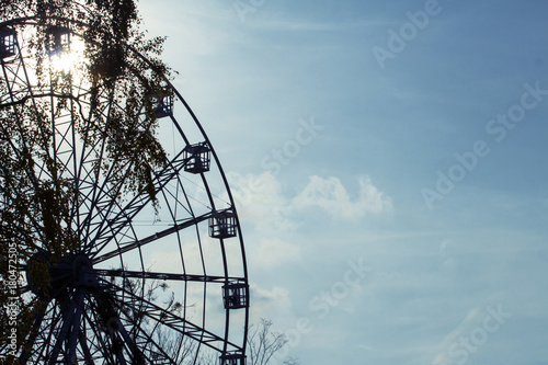 silhouette of a ferris wheel on a background of a sunny sky toned