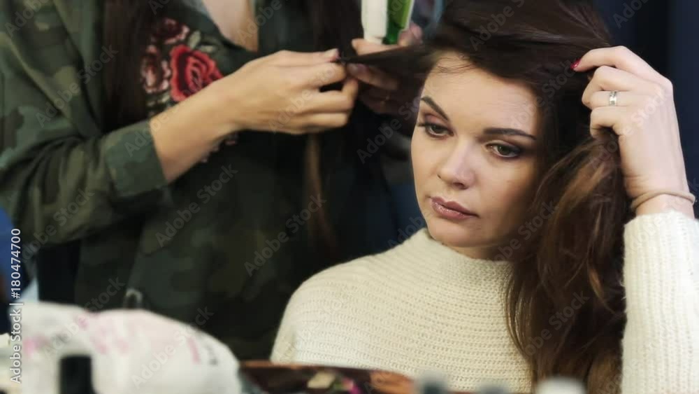 Hair stylist making ringlets to brunette woman. Hairdresser working with beautiful woman hair in hairdressing salon Hair stylist making ringlets to brunette woman. Hairdresser working with beautiful woman hair in hairdressing salon