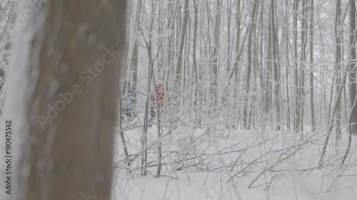 Two skiers make their way down a path while trees wipe the lens