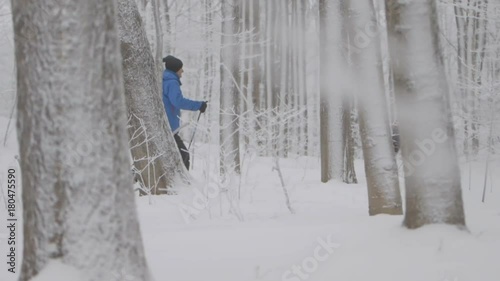 Two skiers push their way down a path and stop for a second