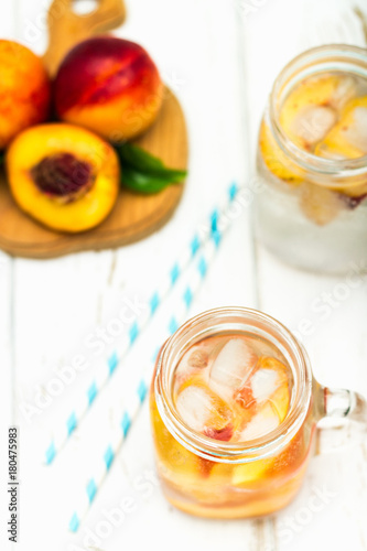 Homemade iced lemonade with ripe peaches. Fresh peach ice tea in a mason jar. Top view.