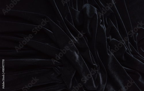 Dark black velvet fabric, wave, draperies. Beautiful textile backdrop. Close-up. Top view 