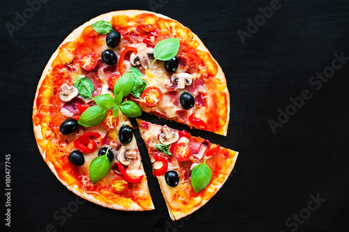 Mozarella Pizza slices with melting cheese and olives served at a pizzeria or restaurant on black board with copy space