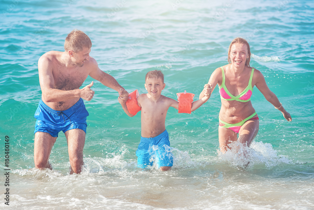 Family of three people getting out from the sea water. Front view. Family of three people getting out from the sea water. Front view.
