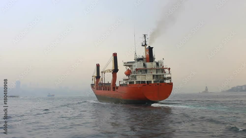 Cargo ship sailing in mist. Tracking shot of the industrial ship. Back view of the red cargo container ship. Istanbul in smog with a cargo ship pass through slowly Cargo ship sailing in mist. Tracking shot of the industrial ship. Back view of the red cargo container ship. Istanbul in smog with a cargo ship pass through slowly